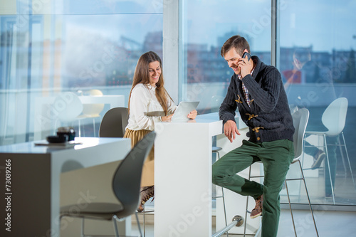 Happy young couple with mobile phones sitting at the coffee shop