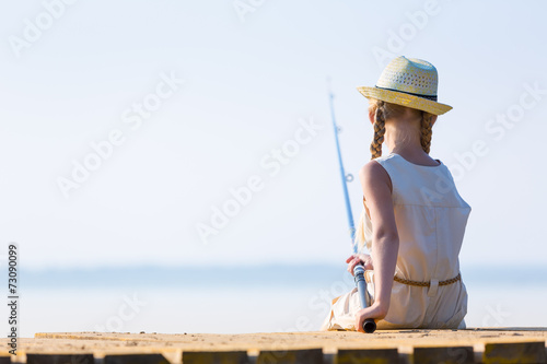 Girl in a dress and a hat with a fishing rod