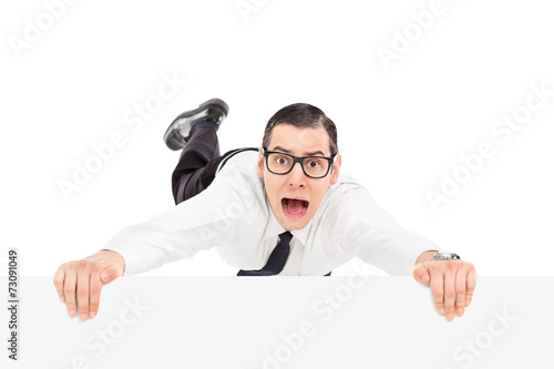 Scared man holding on to the edge of a panel
