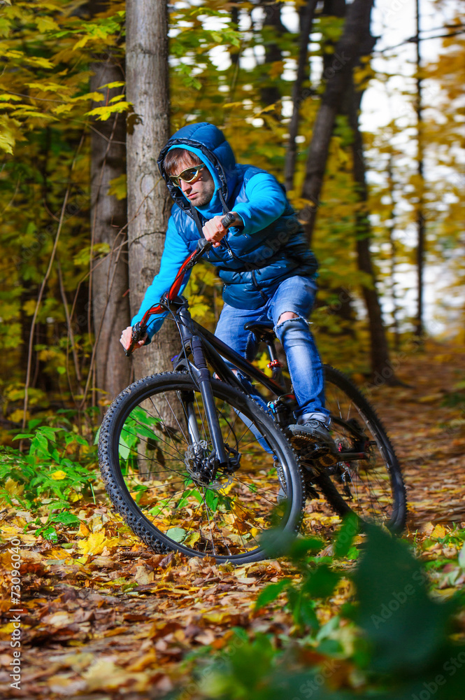 Extreme cyclist riding on mountain bike in autumn forest Extreme cyclist riding on mountain bike in autumn forest