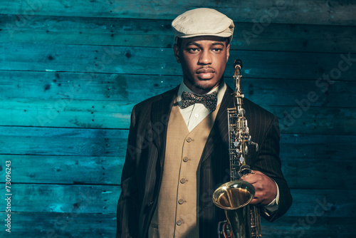 Canvas Print Vintage african american jazz musician with saxophone in front o