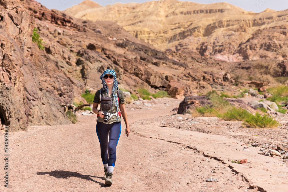 Woman photographer walking desert canyon.