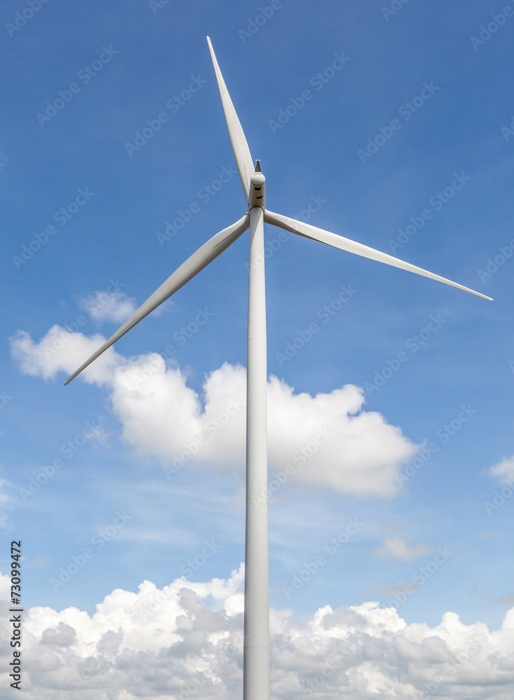 The giant wind turbine stands against cloudy blue sky background