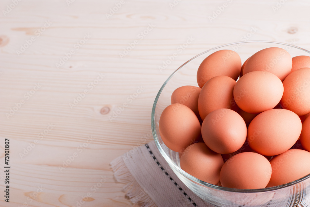 brown eggs in a large glass bowl on a light wooden table view brown eggs in a large glass bowl on a light wooden table view
