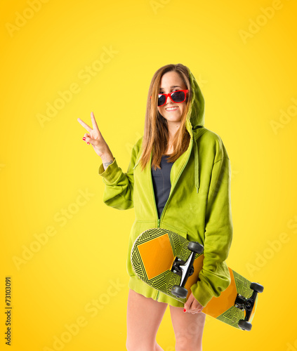 Young girl doing victory gesture over yellow background