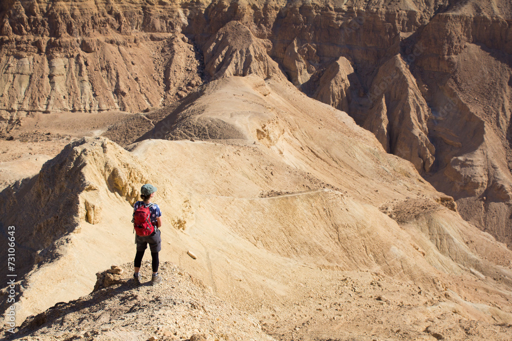 Woman standing desert mountain peak ridge.