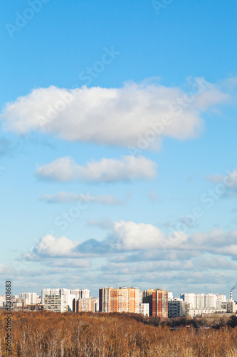 white clouds in blue sky over houses in autumn day