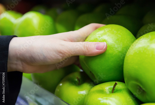 Business woman is choosing apples in the supermarket
