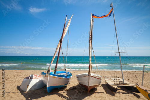 Small sailing boats lay on the sandy beach in Calafell town