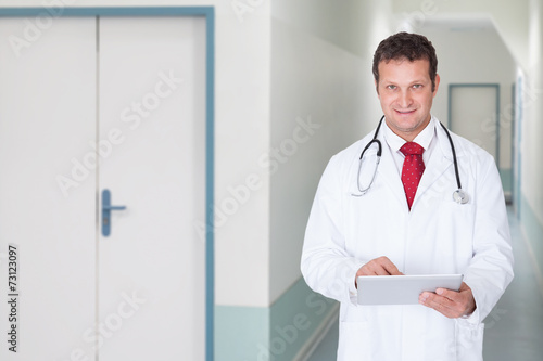Doctor Using Digital Tablet In Hospital Corridor