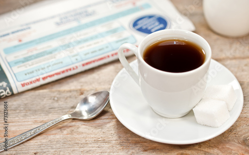 Cup of coffee and newspaper on a wooden table