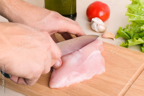 Man's hands cutting chicken
