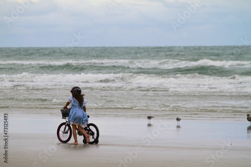 Girl walking with her bike along the beach