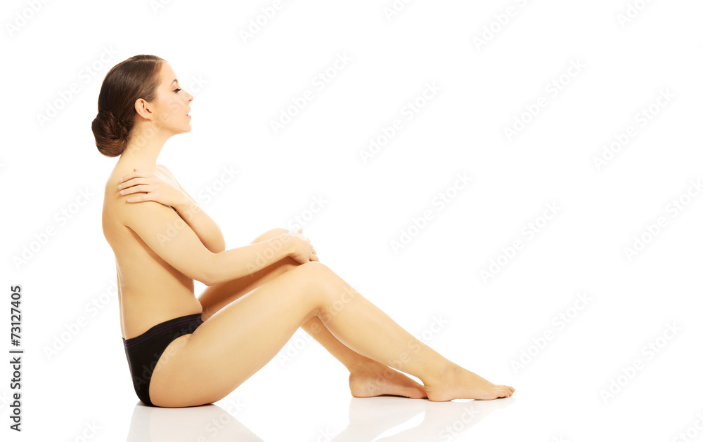 Nude woman in panties sitting on the floor
