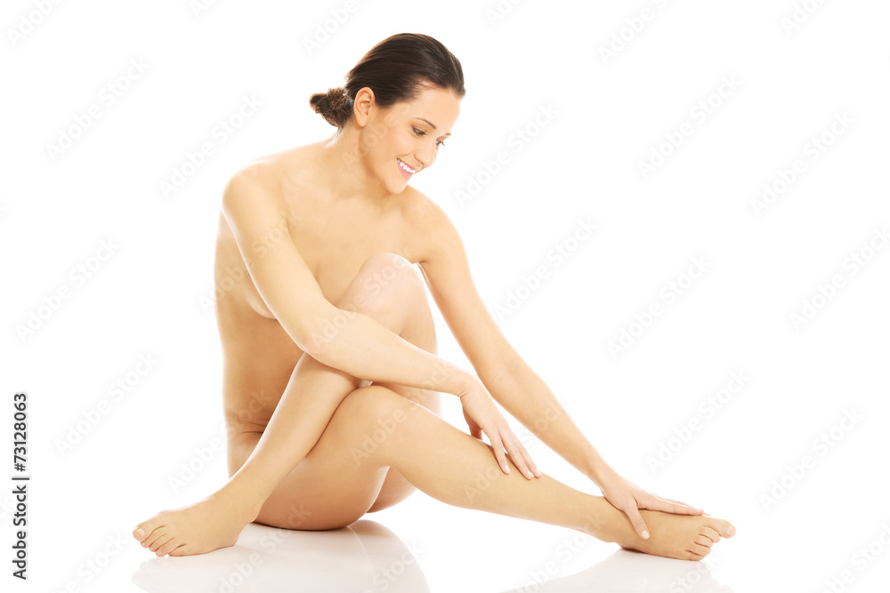 Obraz premium Nude woman sitting and touching her feet