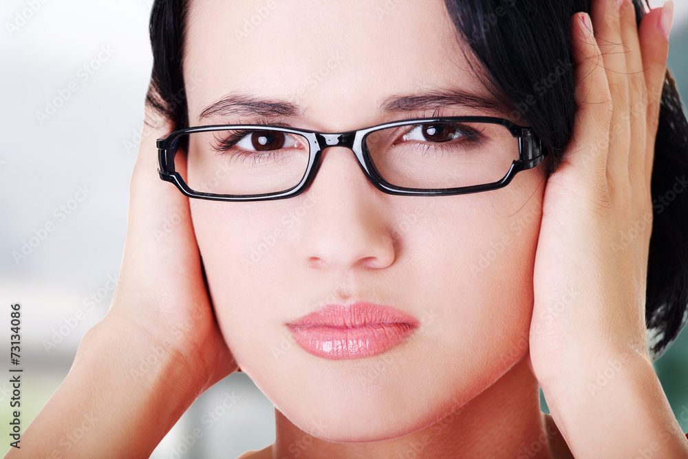 Closeup of frustrated young woman holding her ears Closeup of frustrated young woman holding her ears