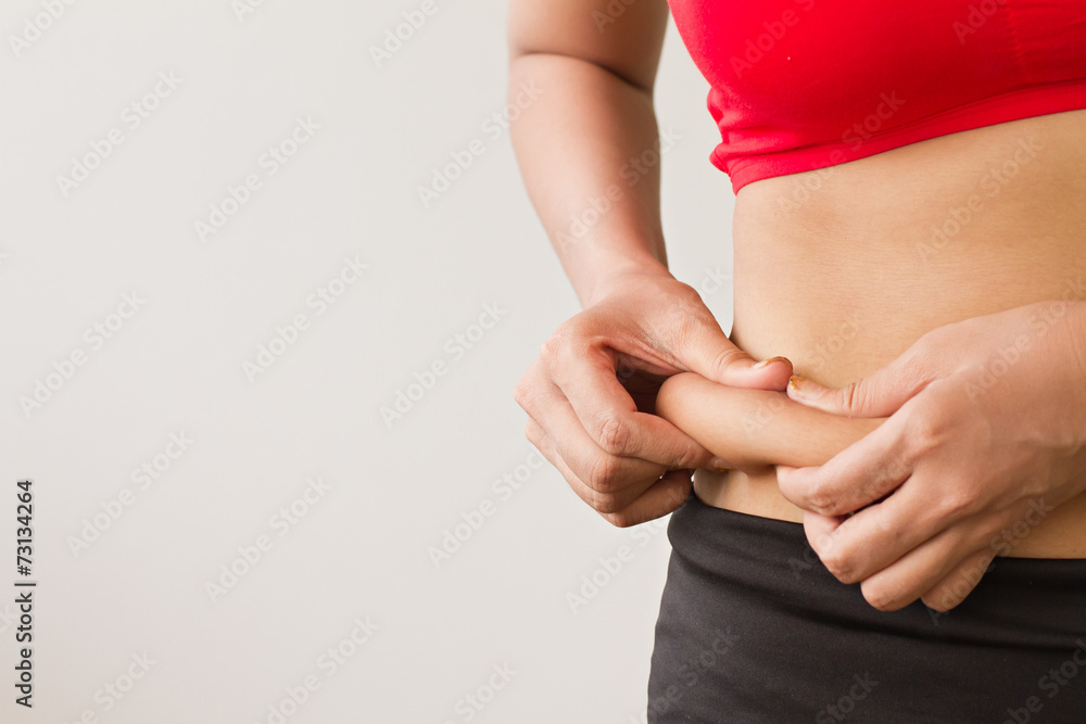 Woman's hand pinching her excess belly fat - obrazy, fototapety, plakaty 
