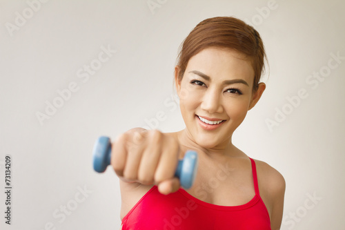 attractive, smiling woman model with dumbbell punching at you