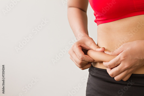 Woman's hand pinching her excess belly fat
