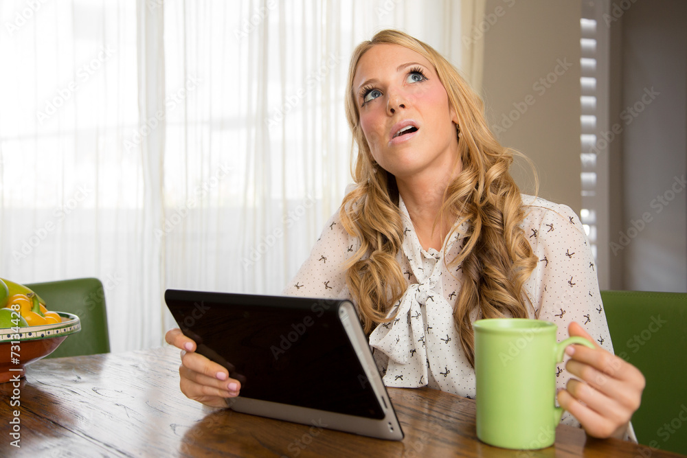 Woman seems worried while reading information on her tablet Woman seems worried while reading information on her tablet