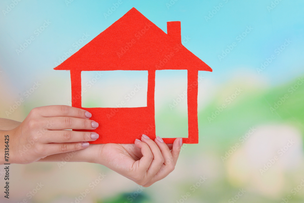 Woman hands holding paper house on bright background Woman hands holding paper house on bright background