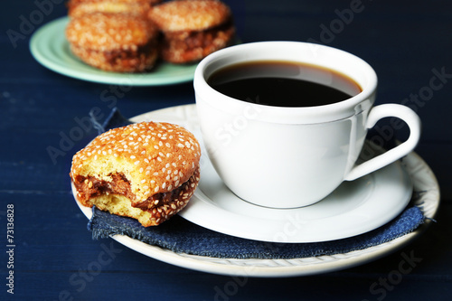 Cup of coffee with tasty cookie on color wooden background