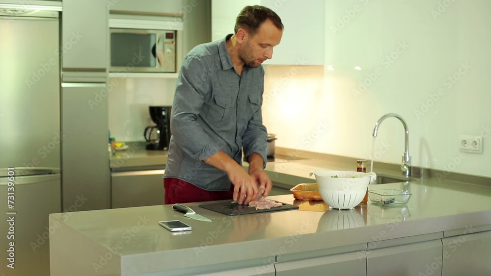 Man washing and slicing chicken breast on chopping board Man washing and slicing chicken breast on chopping board