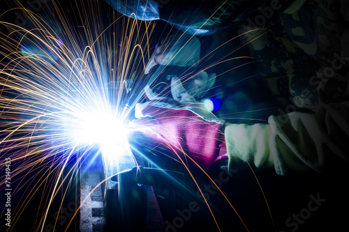 Employee welding steel structures with sparks.