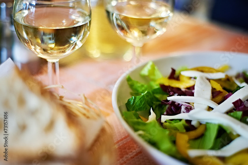 Glasses of white wine and salad on table cafe