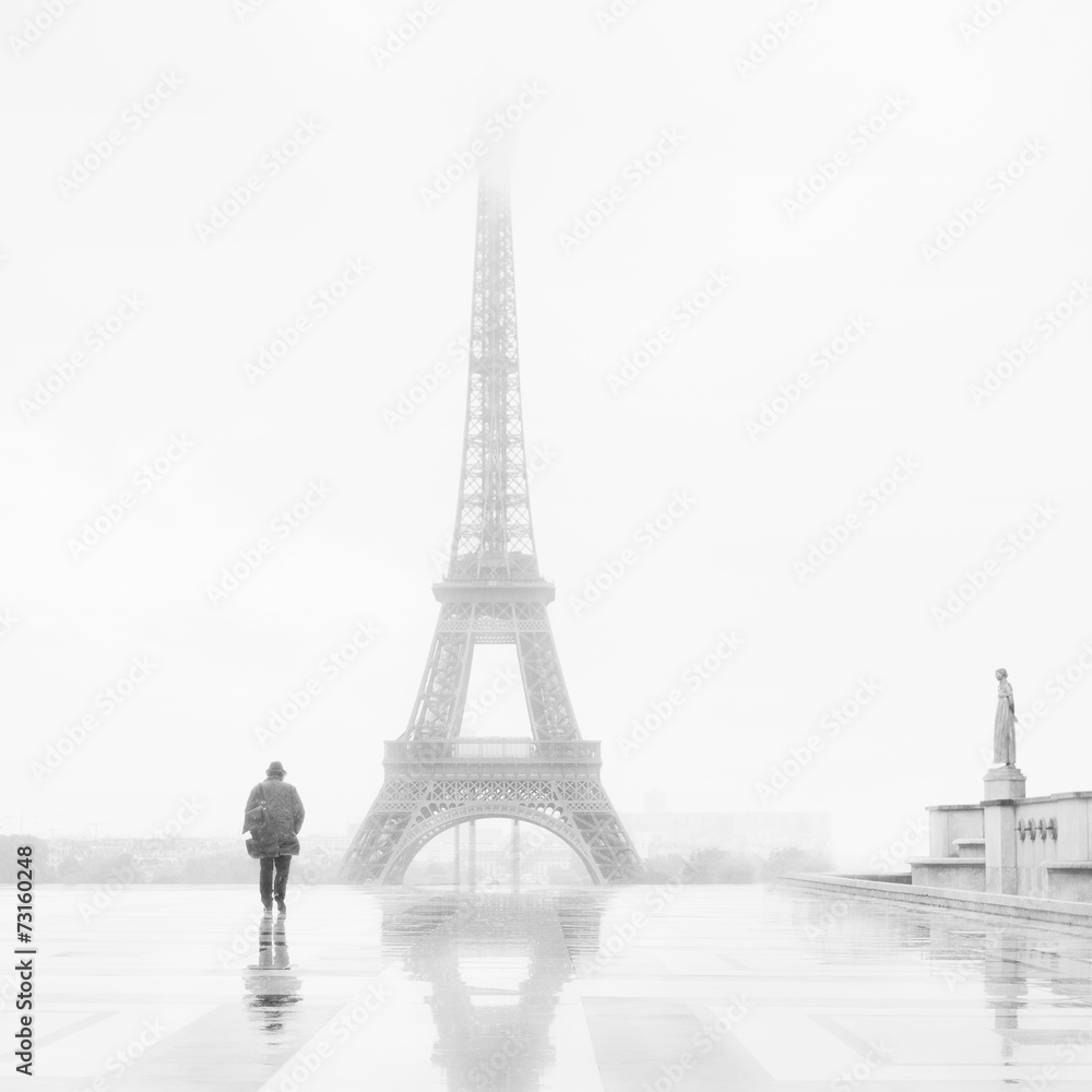 Man and the Eiffel Tower, rain and fog.