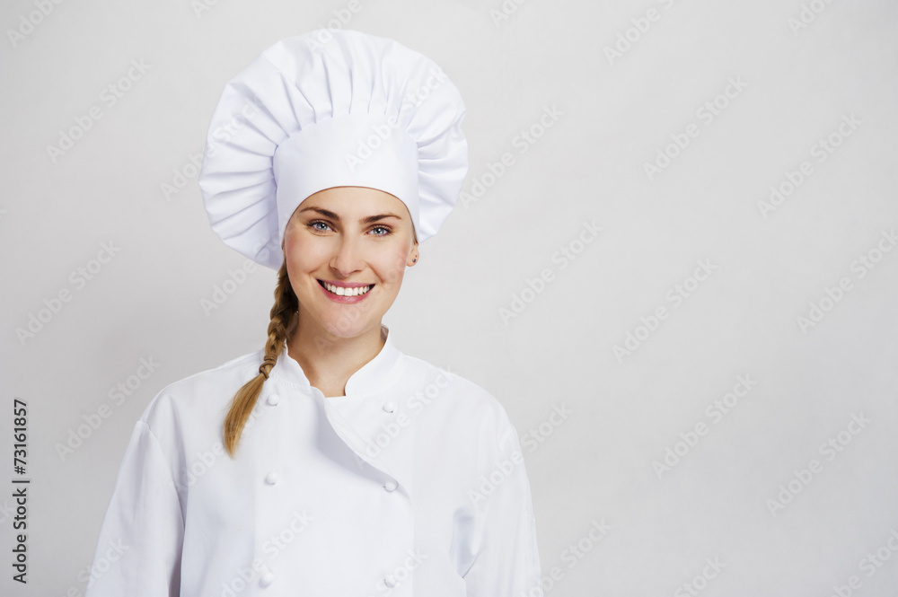 A young, female chef in a traditional hat and coat. A young, female chef in a traditional hat and coat.