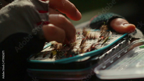 the hand touches front fly in a fly box