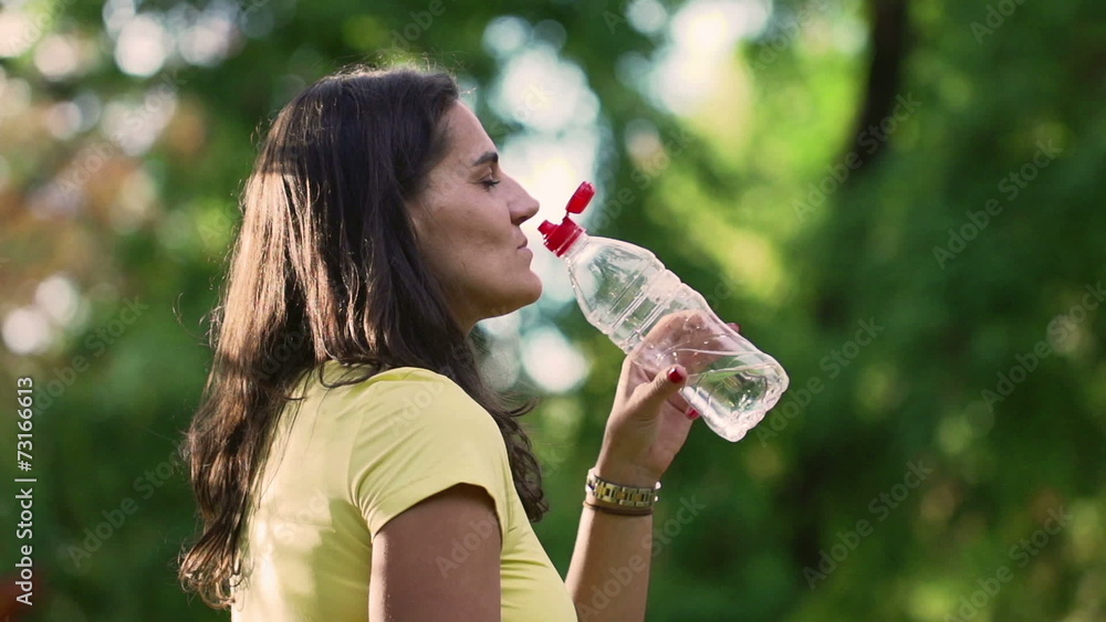 Sporty woman drinking water in park, slow motion, steadycam Sporty woman drinking water in park, slow motion, steadycam