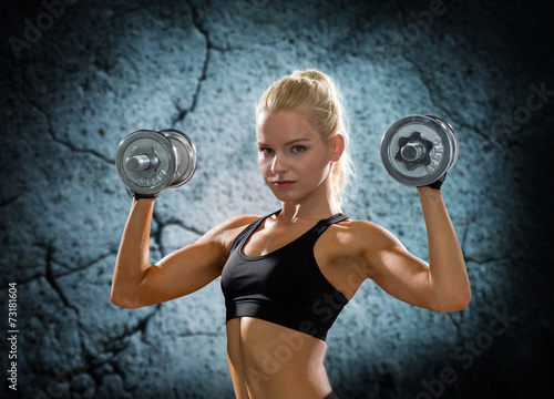 young sporty woman with dumbbells flexing biceps