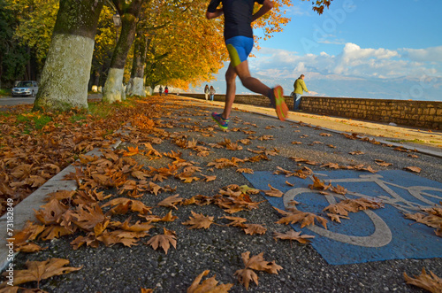 runner in autumn road with yellow leaves