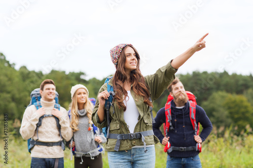 smiling hikers with backpacks pointing finger