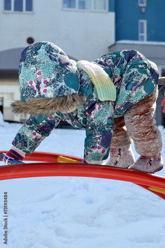 Little girl climbing  on a snow playground