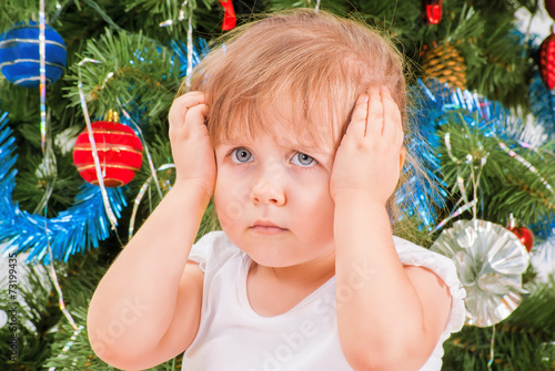 Upset and distraught little girl near the Christmas tree