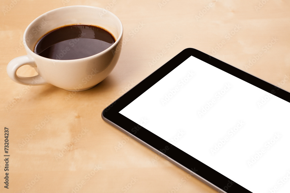 Tablet pc with empty space and a cup of coffee on a desk Tablet pc with empty space and a cup of coffee on a desk