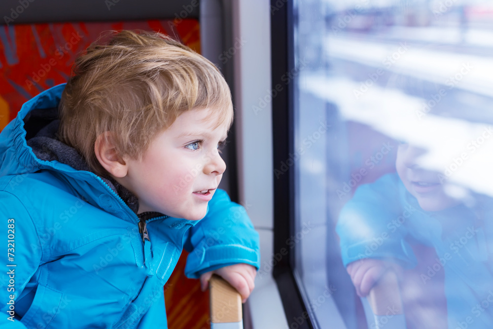 Little kid boy traveling and looking out train window outside Little kid boy traveling and looking out train window outside
