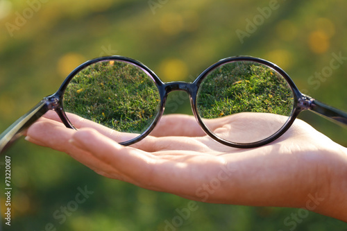 Vision concept. Glasses in hand on green background