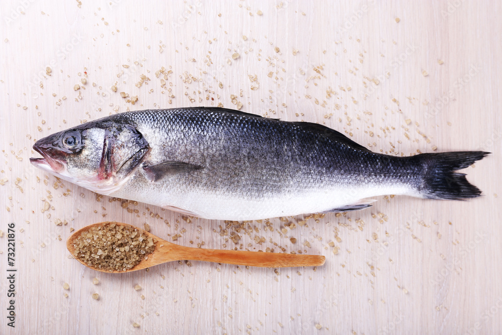 Fresh fish and salt in spoon on wooden background Fresh fish and salt in spoon on wooden background