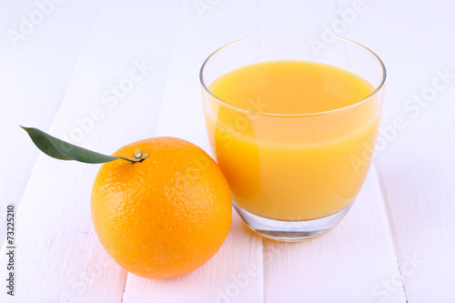 Glass of fresh orange juice on white wooden table