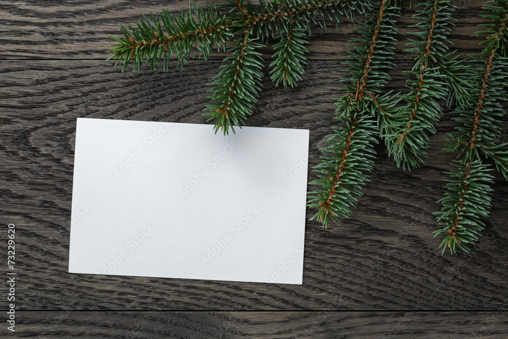 fir branch with paper card on oak table from above fir branch with paper card on oak table from above