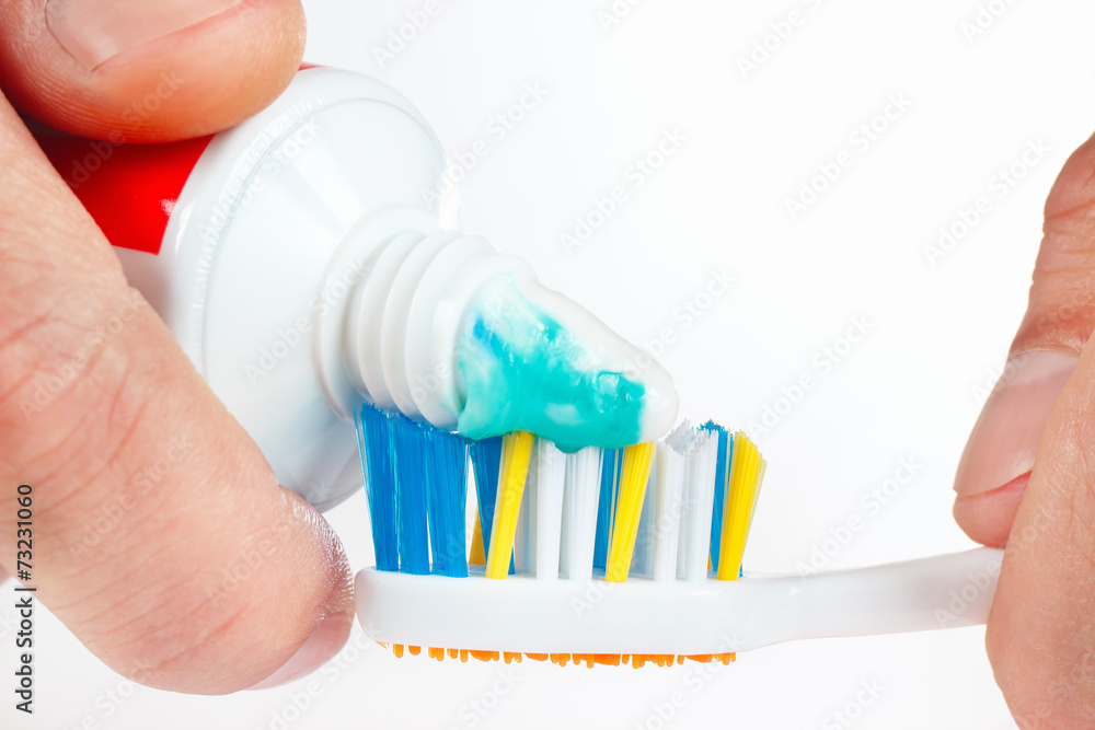 Hand squeezes the color toothpaste on the toothbrush