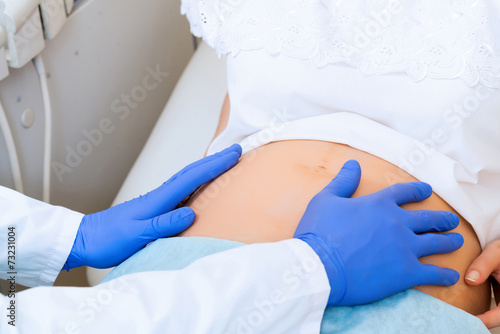 of doctor's hands on the belly of a pregnant woman