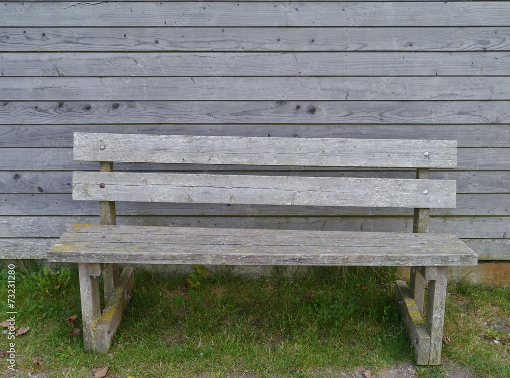 A wooden bench opposite a wooden wall
