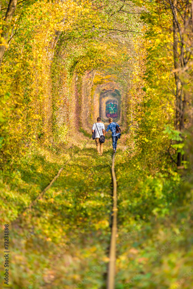 Couple walking towards the train at fall landscape tunnel Couple walking towards the train at fall landscape tunnel