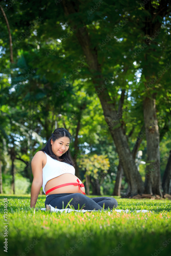 Beautiful pregnant asian woman relaxing in the park with red rib Beautiful pregnant asian woman relaxing in the park with red rib