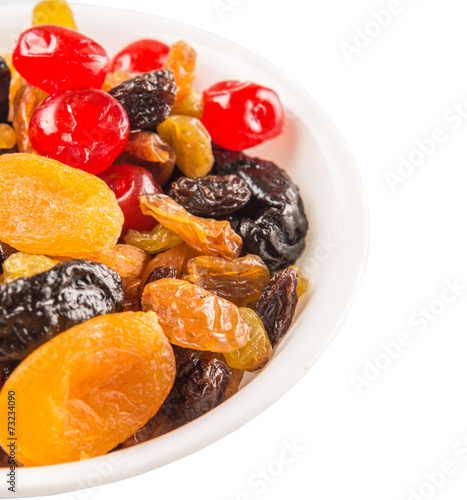 Mix variety of dried fruit in white bowl over white background